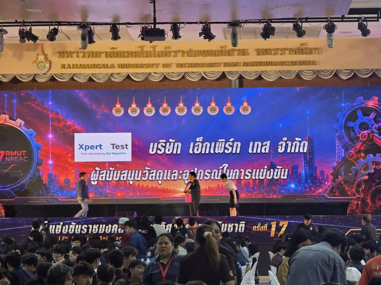 ชื่อบริษัท Expert Test แสดงบนเวทีในฐานะผู้สนับสนุนวัสดุและอุปกรณ์ในการแข่งขัน